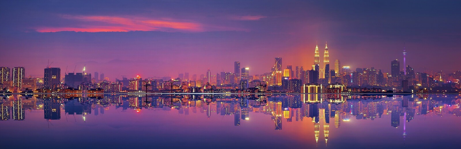 Kuala Lumpur skyline at dusk with the Petronas Towers reflected in the lake